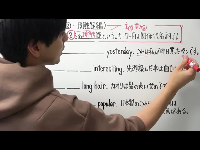 A person writing on a whiteboard with Japanese text, filling in blanks and discussing topics like "yesterday," "interesting," "long hair," and "popular."